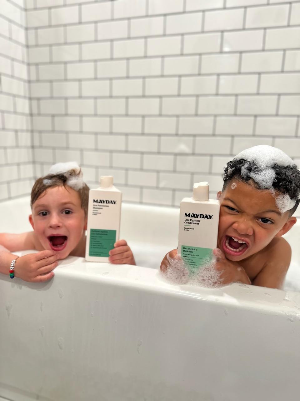 Two children in a bubble bath holding MAYDAY shampoo and conditioner