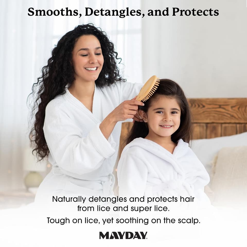 Mother brushing her smiling daughter's hair, both in white bathrobes
